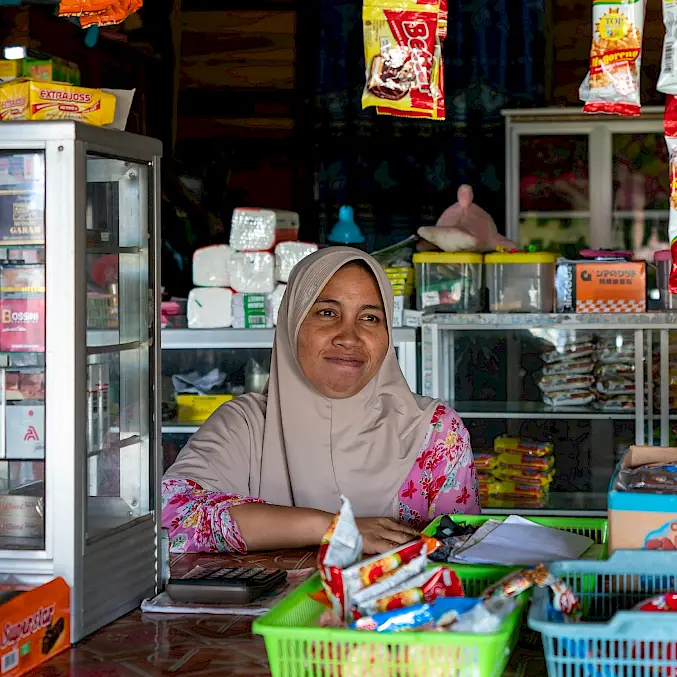 Die lokale Unternehmerin betreibt ihren Kiosk mithilfe von BOS-Mikrokrediten und trägt zur wirtschaftlichen Entwicklung und Gemeinschaftsstärkung in Indonesien bei. © Andrew Suryono | BOSF | BOS Schweiz
