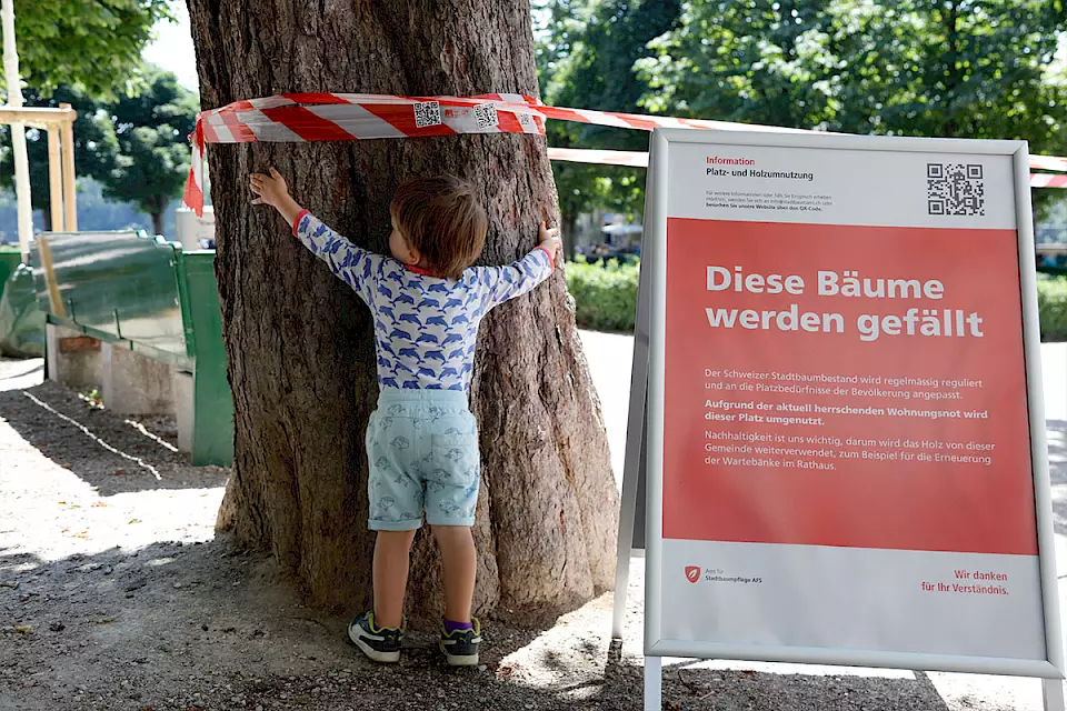 Ein Kind umarmt an der PR-Aktion von BOS Schweiz einen Baum