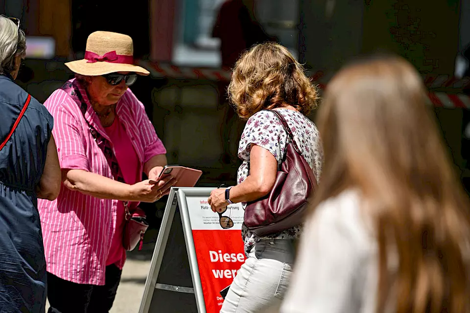 Frauen scannen den QR-Code auf einem Plakat der PR-Aktion von BOS Schweiz