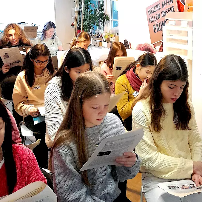 Grosses Bild:  Von Kindern für Kinder: Interessiert lesen die Mädchen die Reportage einer Schülerin über CEO Dr. Sophia Benz.